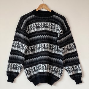 May include: Black and white patterned jumper with a crew neck and long sleeves. The pattern features llamas and geometric designs.