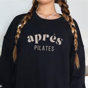 May include: Black sweatshirt with the text "apr&egrave;s PILATES" in a light brown color.