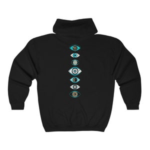 Pu&ograve; includere: Felpa con cappuccio nera con una fila verticale di sette disegni di occhi maligni blu e bianchi sul retro.
