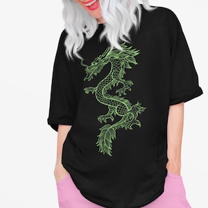 K&ouml;nnte beinhalten: Schwarzes, &uuml;bergro&szlig;es T-Shirt mit einem neongr&uuml;nen Drachendesign. Der Drache ist detailliert mit Schuppen und flie&szlig;enden Linien. Das T-Shirt ist l&auml;ssig geschnitten und f&uuml;r den Alltag geeignet.
