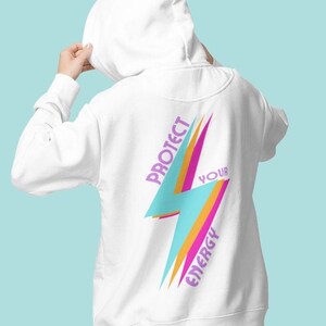 K&ouml;nnte beinhalten: Wei&szlig;er Hoodie mit einem Blitz-Motiv und dem Text "Sch&uuml;tze deine Energie" in Lila und Orange.