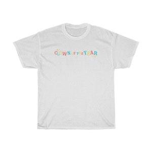 May include: White t-shirt with the text "CLOWN OF THE YEAR" in colorful letters with stars on either side.