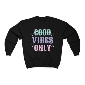 May include: Black sweatshirt with the text "GOOD VIBES ONLY" in pastel colors with stars around the words.