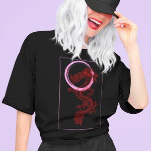 May include: A black t-shirt with a red dragon graphic and a pink circle around it. The dragon is stylized and has a detailed design.