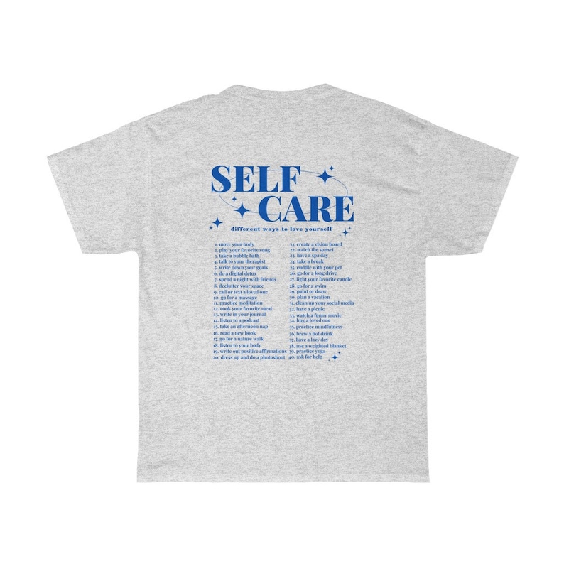 May include: Gray t-shirt with a blue graphic that says "SELF CARE" and a list of different ways to love yourself. The graphic is surrounded by stars.