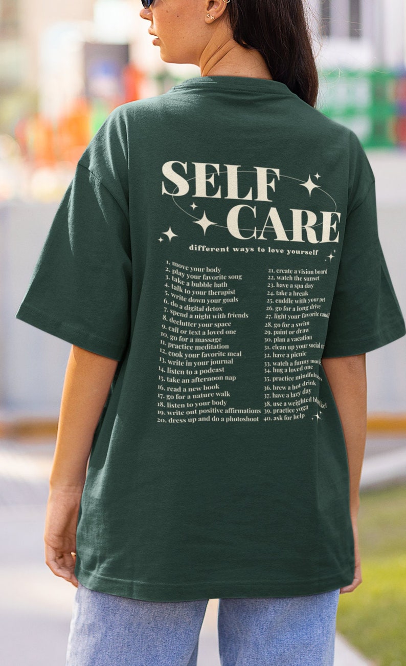 May include: A green t-shirt with the text "SELF CARE" in a white circle with stars. The text "different ways to love yourself" is below the circle. A list of 40 self-care tips is printed on the back of the shirt.
