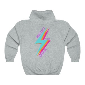 K&ouml;nnte beinhalten: Ein grauer Kapuzenpullover mit einem bunten Blitz-Motiv und dem Text "Sch&uuml;tze deine Energie" auf der R&uuml;ckseite.