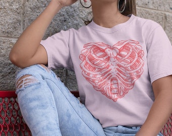 May include: A pink t-shirt with a red anatomical heart design. The heart is made up of a rib cage.