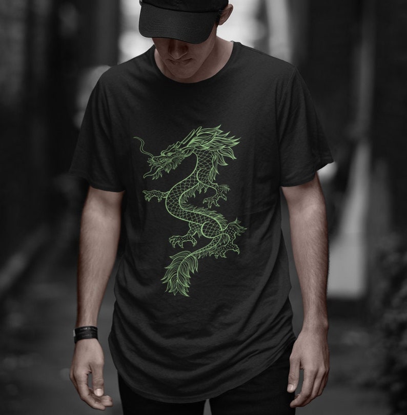 K&ouml;nnte beinhalten: Schwarzes T-Shirt mit einem neongr&uuml;nen Drachendesign. Der Drache ist detailliert, mit einem langen, geschwungenen K&ouml;rper und flie&szlig;enden Merkmalen. Das T-Shirt ist ein klassischer Rundhalsausschnitt aus weichem Material.