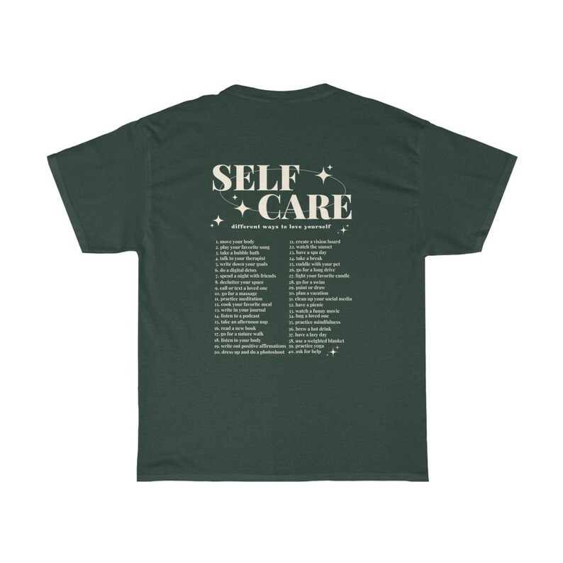 May include: A dark green t-shirt with the text "SELF CARE" in a cream color. The text is surrounded by small stars and a circle. Below the text is a list of 26 self-care tips.