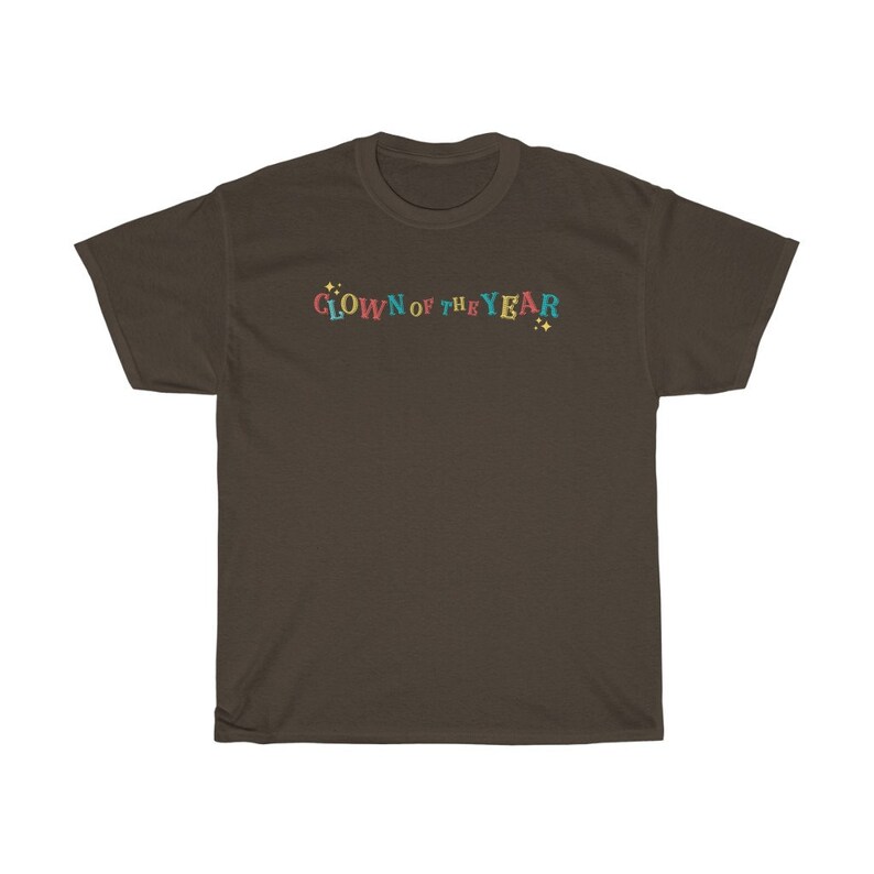 May include: A brown t-shirt with the text "CLOWN OF THE YEAR" in colorful letters with yellow stars on either side.
