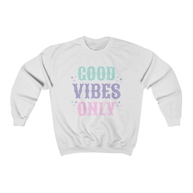 May include: White sweatshirt with the text "GOOD VIBES ONLY" in pastel colors. The text is in a vintage style font with stars around it.