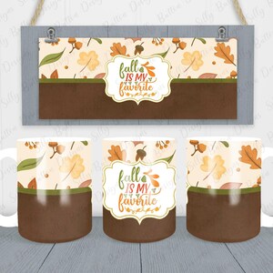 May include: Three white ceramic mugs with a brown and green autumn leaf design. The mugs have a brown band around the middle and feature the text "fall is my favourite" in a brown frame.