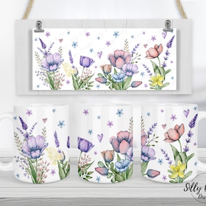 Op de afbeelding: Witte keramische mok met een bloemenontwerp met roze, paarse en gele bloemen. Het ontwerp omvat lavendel, tulpen en narcissen. De mok is een geweldig cadeau voor elke gelegenheid.