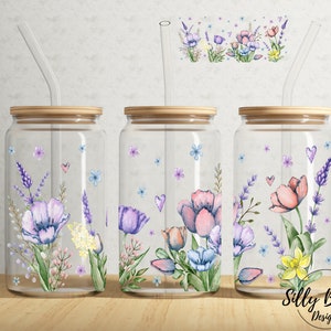 Könnte beinhalten: Drei Glasbehälter mit Holzdeckeln und Strohhalmen. Jeder Behälter hat ein florales Design mit lila, rosa und gelben Blumen. Die Behälter stehen auf einer Holzoberfläche. "Silly Button Designs" ist in der unteren rechten Ecke des Bildes gedruckt.