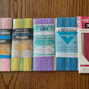 May include: Five packages of lace seam binding in various colors, including pink, yellow, lavender, blue, and cranberry. Each package contains 3 yards of lace and is labeled with the brand name "Wrights" and the price "39c".