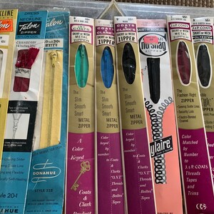 May include: A collection of vintage zipper packages, featuring various brands like Talon, Coats & Clark, and Ylaire. The packages showcase different zipper types, including metal, nylon coil, and polyester, with various colors and sizes. The packages feature text like "The Slim Smooth Smart Metal Zipper" and "Fashion Right Zipper".