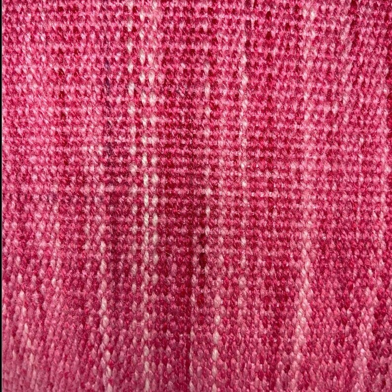 Puede incluir: Primer plano de una tela tejida rosa y blanca con un patr&oacute;n texturizado.