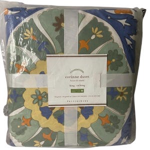 May include: A green, blue, yellow, and orange patterned king-sized duvet cover with a white label that reads "FOUNDATIONS corinne duvet housse de couette king - cal king CERTIFIED OEKO-TEX" and "tris grandes grand cal. (108 x 92 INCHES - 274 x 233 CM) POTTERY BARN".