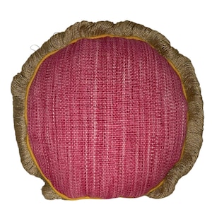 Puede incluir: Una almohada redonda de color rojo con un ribete de flecos dorados. La almohada est&aacute; hecha de una tela texturizada.