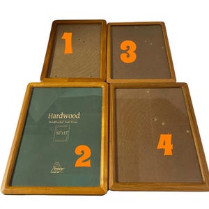 May include: Four wooden picture frames with a light brown finish. One frame has a green backing with the text "Hardwood" and "10x13". The other frames have a brown backing. Each frame has an orange number in the corner.