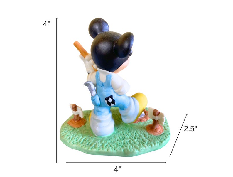 Peut inclure: Une figurine en c&eacute;ramique de Mickey Mouse habill&eacute; d'une salopette bleue et d'un chapeau jaune, tenant une pelle et debout sur une base verte avec des accents bruns. La figurine mesure 10 cm de haut et 10 cm de large.