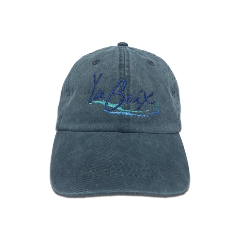 K&ouml;nnte beinhalten: Eine tealfarbene Baseballkappe mit dem gestickten Text "La Croix" in Schreibschrift. Die Kappe hat einen gebogenen Schirm und einen Stoffriemenverschluss. Die Kappe ist aus einem weichen, strapazierf&auml;higen Material gefertigt.