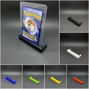 May include: A black plastic card holder stand with a clear plastic card protector. The card protector has a Pokemon card inside with a Poké Ball graphic. The stand is also available in white, blue, green, yellow, and red.