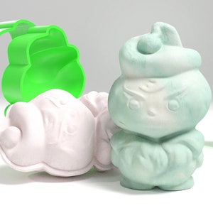 以下が含まれることがあります： 雪だるまの形をした石鹸を作るための緑色のプラスチック製の型が3つあります。1つの型は薄い緑色の石鹸で満たされ、もう1つは白い石鹸で満たされ、3つ目は空です。