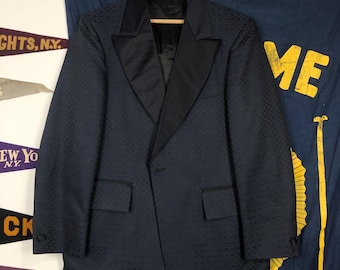 May include: A dark blue patterned blazer with a black satin shawl collar and a single button closure. The blazer has a quilted texture and is in good condition.