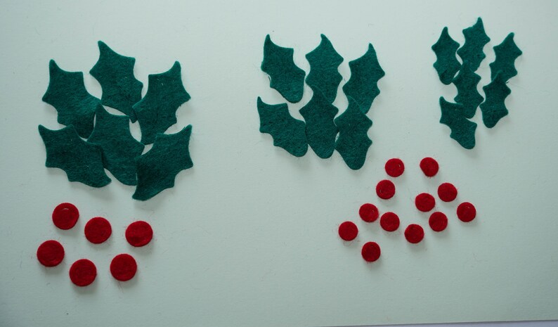 May include: Assortment of felt holly leaves and red felt berries for crafting projects.