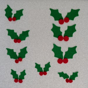 May include: Ten green felt holly leaves with red felt berries. The holly leaves are arranged in pairs with the berries in the center of each pair.