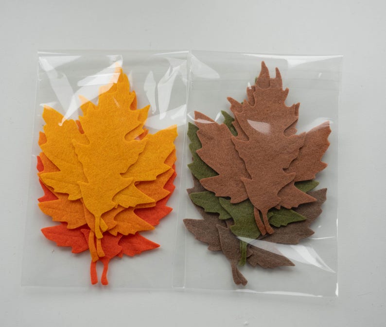 May include: Two packages of felt leaf cutouts. One package contains orange, yellow, and red leaves. The other package contains brown and green leaves.
