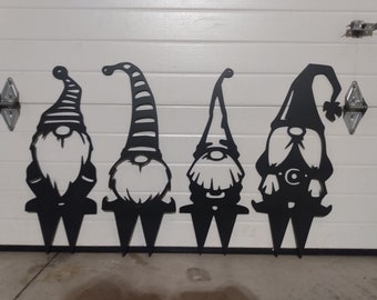 May include: Four black metal gnomes with different hat designs. The gnomes are standing on spikes and are ready to be placed in the ground.
