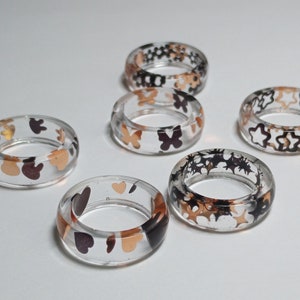Black and Gold Bunnies, Butterflies, Flower Blossoms, Hollow Stars, Hearts, and 4 Point Stars In a Clear Resin Band