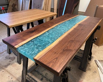May include: A wooden table top with a turquoise epoxy river running down the center. The table top is made of walnut wood and is supported by black metal legs.