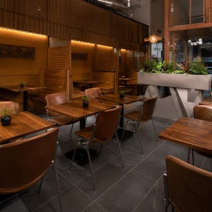 Peut inclure: Intérieur d'un restaurant avec tables et chaises en bois. L'espace est éclairé d'une lumière chaleureuse et présente un design moderne. Les tables sont ornées de petites plantes en pot. Le restaurant semble vide.