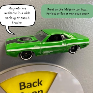 May include: A green toy car magnet with black racing stripes and white accents. The magnet has the text "Challenger" and "Mopar". Text bubbles say "Magnets are available in a wide variety of cars & trucks" and "Great on the fridge or tool box... Perfect office or man cave decor".