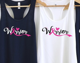 May include: Three tank tops with the word "Warrior" written in white script with a pink ribbon and heart design. The tank tops are navy blue, white, and navy blue.