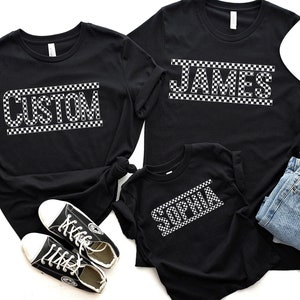 May include: Three black t-shirts with white checkered text. The shirts say "CUSTOM", "JAMES", and "SOPHIA".