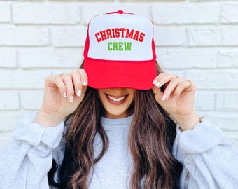 May include: A red and white trucker hat with the text "Christmas Crew" in green and red letters.