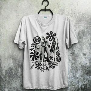 Könnte beinhalten: Weißes T-Shirt mit einem schwarz-weißen Grafikdruck einer Band mit einem psychedelischen Design. Das Design beinhaltet Spiralen, Sterne und Blumen.