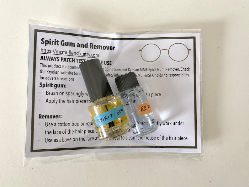 May include: Two small clear glass bottles with black caps containing spirit gum and remover, labeled with blue and orange tape. They are packaged in a clear plastic bag with an instructional card titled Spirit Gum and Remover.