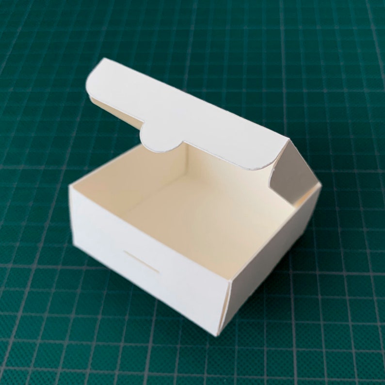 May include: A white cardboard box with a hinged lid, open and ready to be filled. The box is made of sturdy cardboard and has a clean, simple design.