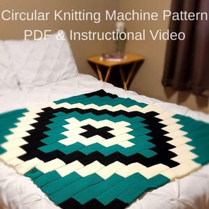May include: A knitted blanket with a geometric pattern in teal, black, and cream colors. The blanket is displayed on a bed with white bedding. The image also includes text that reads "Circular Knitting Machine Pattern PDF & Instructional Video."