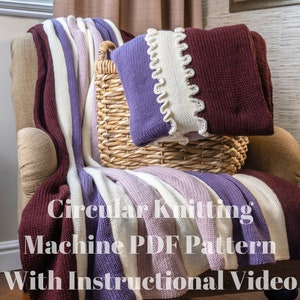 May include: A knitted blanket and cushion in shades of purple, white, and burgundy are draped over a chair. The blanket has vertical stripes, and the cushion has a ruffled edge. A woven basket sits on the chair. The text on the blanket reads: "Circular Knitting Machine PDF Pattern With Instructional Video."