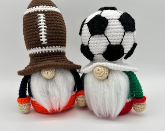 May include: Two crocheted gnomes, one wearing a brown football hat and the other wearing a white and black soccer ball hat. Both gnomes have white beards and are wearing colorful clothing.