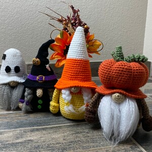 Peut inclure: Quatre gnomes en crochet habillés sur le thème d'Halloween et d'automne. Les gnomes portent un costume de fantôme, un chapeau de sorcière, un costume de maïs sucré et un chapeau de citrouille.