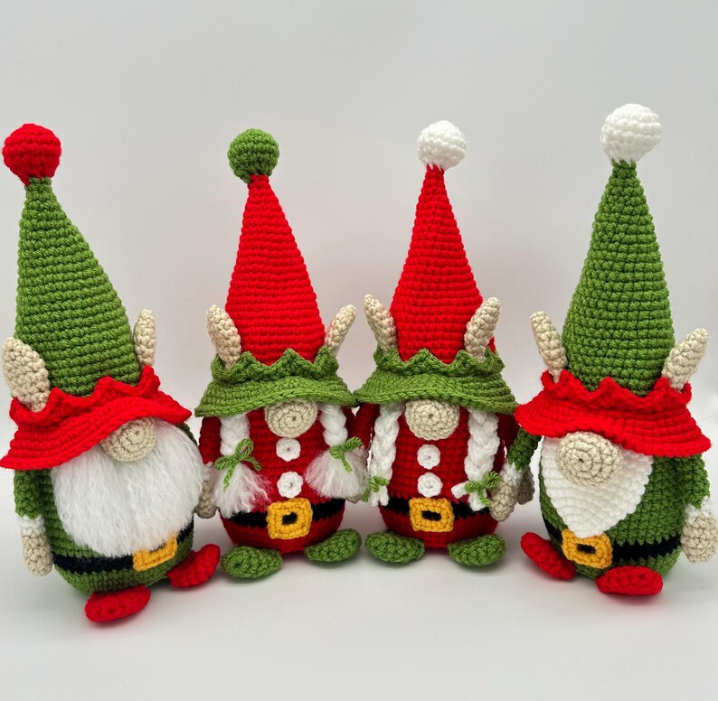Four festive crochet elf gnomes in red, green, and white Christmas outfits with tall hats, braids, and belts, handmade amigurumi figures shown for the downloadable PDF crochet pattern.