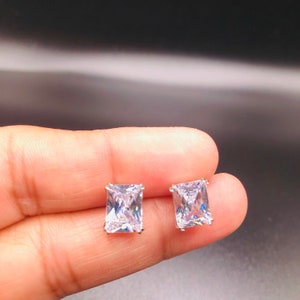 Peut inclure: Une paire de boucles d'oreilles en argent avec de grandes pierres de zircone cubique carrées et transparentes.